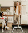 Two people near a trailer using an Aluminum Step Ladder Work Platform Drywall Bench Folding Heavy Duty Extra Large Portable No Assembly Needed Lightweight Pro Grade Aluminum EN131 Certified 330 Lbs Perfect For Ceiling Work Painting And Elevating Projects as a step.