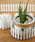 Four Piece 35 Inch Fairy Garden Wood Picket Fence Set For Dollhouse Miniature Village Landscape And DIY Diorama Projects White Color Durable Moisture Proof Great For Tiny Plant Pots And Cute Garden Scenes used around a plant pot