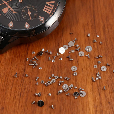 100 Piece Watch Screw Set With Micro Battery Clamp Screws, Stainless Steel Assortment for Watchmaking on wooden surface