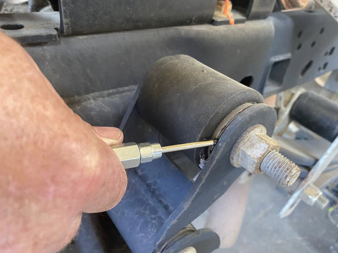 Lincoln 5803 hand-held grease gun needle nozzle with hardened steel tip, 1/8" NPT, 2.76" length, inserted into grease fitting