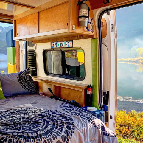 Cozy camper interior with "Happy Camper" sign above bed; Funny Camping Decor Sign For RV And Camper Interiors, Easy Install Wall Art.