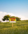 Yard Sale EZ Kit Neon Yellow Signs 11 By 14 Inches in grassy field with clear sky and trees.
