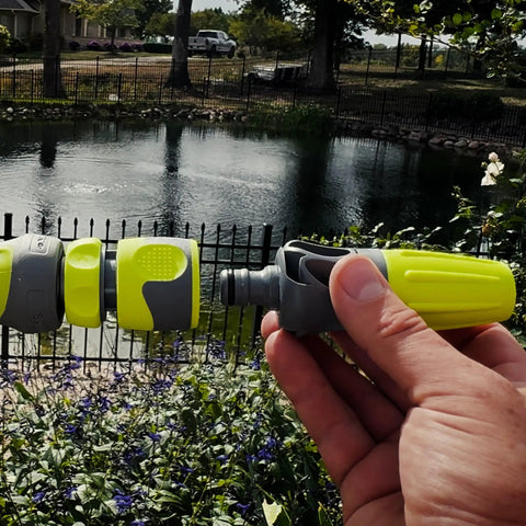 Garden Hose Nozzle Kit, 3-Piece With Quick Connect Sprayer And Flow Stop Adapter held near a backyard pond
