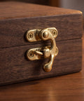 Close-up of a golden metal vintage swing bag clasp closure lock retro latch on a wooden jewelry box.
