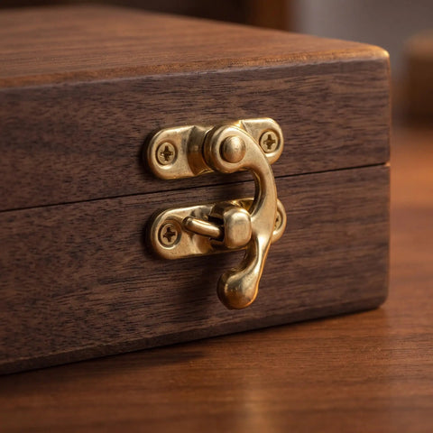 Close-up of a golden metal vintage swing bag clasp closure lock retro latch on a wooden jewelry box.