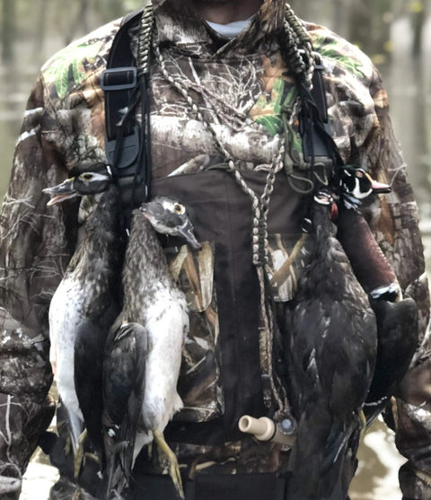 Rugged Paracord Bird Tote Carrier With 12 Drop Slip Ring System holding ducks on a camouflaged hunter's chest for easy carry.