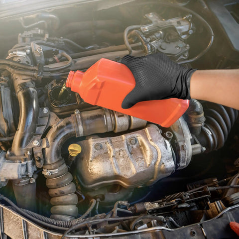 Hella Durable Black Nitrile Safety Gloves With Sick PyraGrip Texture For Superior Traction On Greasy Jobs pouring oil into a car engine.