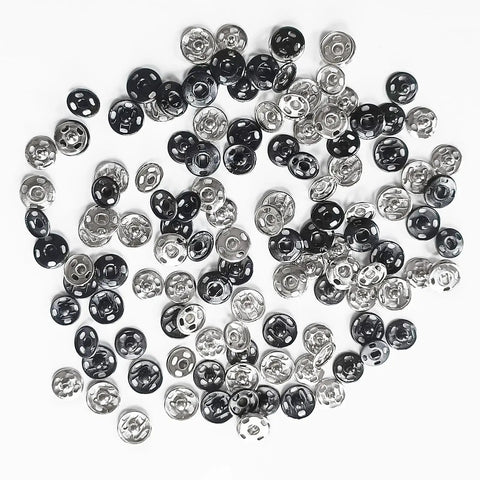 120 Set Sew-On Metal Snap Buttons Pack With 8mm And 10mm Sizes In Black And Silver scattered on white surface