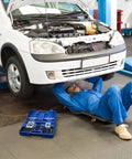 Thinking Process: mechanic under raised white car using 14 pc anti slip bearing puller kit in blue case