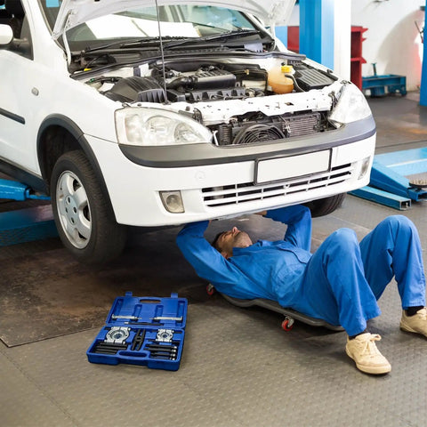 Thinking Process: mechanic under raised white car using 14 pc anti slip bearing puller kit in blue case
