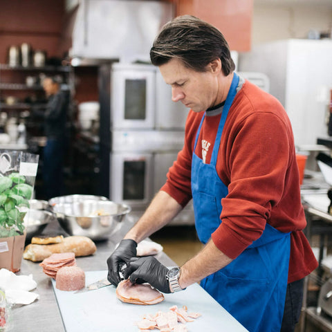 AMMEX X3 black nitrile disposable gloves being worn by a kitchen worker preparing food