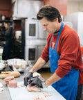 Chef wearing Black Nitrile Gloves 3 Mil Disposable for Cooking and Food Prep, cutting ham in a kitchen, latex free, textured grip.