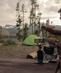 Man using Portable Propane Stove With 10,000 BTU Burner Chrome Anti-Clog Design in a campsite with mountains in the background.