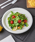 Heavy Duty 150 Count 10 Inch Paper Plates Made From Sugarcane Bagasse White Unbleached Compostable Dinner Plates No Plastic Lining For Parties And Events Durable Eco Friendly Disposable Partyware You Can Feel Good About with salad and lemon slice, on a wire rack with cutlery and a waffle in view.