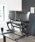 36 Inch Height Adjustable Desk Converter Sit To Stand Riser With Dual Monitor Support in home office setup, black surface
