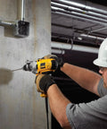 Worker using Corded Hammer Drill Kit With Half Inch Capacity And Ten Amp Power For Masonry Wood And Steel Drilling Dual Mode Hammer And Drill Built For Pros And Serious DIYers Who Need Beefy Power on concrete wall