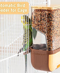 Slick Automatic Bird Feeder With Sturdy Perch And Transparent Seed Bin mounted on cage, filled with seeds, parakeet nearby.