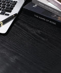 Thick Black Peel And Stick Wallpaper Roll Featuring Hella Durable Self Adhesive PVC Material For Quick Interior Wall Covering With Zero Residue Guarantee on a desk with a laptop and books.