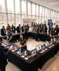 Technology showcase featuring multiple tables with laptops and smartphones in a bright, modern conference setting.