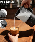 Person pouring milk from a Cafe Quality Home Coffee Bar 350ml Milk Frother And Steamer With Four Modes For Hot And Cold Foam Durable Nonstick Design Fast Heating into a cup