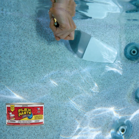A hand applying Heavy Duty Rubberized Waterproof Sealant Paste In Bright White Half Quart Tub to a pool surface for repairs.