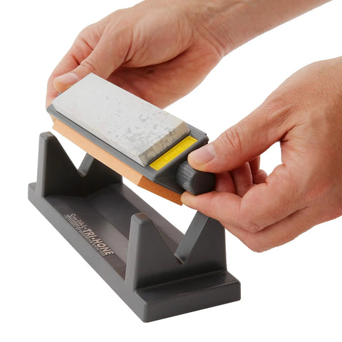 Hands holding 3-stone sharpening system with Tri Hone Stone Sharpening System Three Way Honing With 1000 Grit Fine Arkansas Stone.