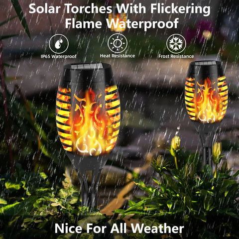 Solar Flickering Flame Outdoor Torch Lights For Garden Decor Waterproof 12 LED Torches in a rainy garden setting.