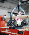 BMWOOD MC-FS7 woodturning steady rest on a red Bauer lathe, turning a wooden spindle with pink wheels.