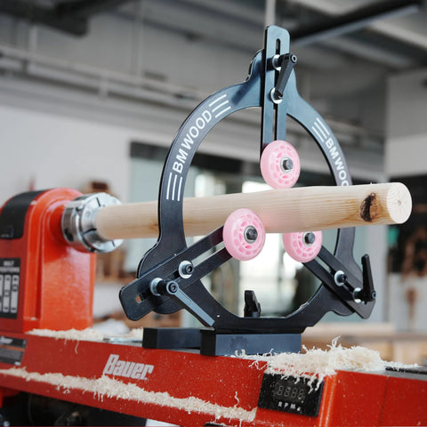 BMWOOD MC-FS7 woodturning steady rest on a red Bauer lathe, turning a wooden spindle with pink wheels.