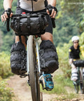 Cyclist using 6.5L Waterproof Front Fork Bike Bag with Roll Top Closure for Road Gravel and MTB Universal Mount on forest trail