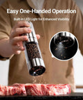 Upgraded Large Capacity Electric Salt And Pepper Grinder Set in use, grinding pepper onto raw meat with LED light and stainless steel finish.