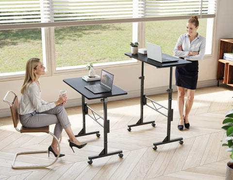 32 Inch Portable Standing Desk On Wheels, Adjustable Height Sit Stand Desk For Small Spaces in use, two women engaging at different heights
