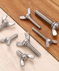 Top Tier 5 Piece 1/4 20 X 3/4 Wing Butterfly Screws crafted from heavy duty 304 stainless steel on a wooden surface.