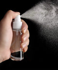 Hand using 2 Pack 1Oz Clear Plastic Travel Spray Bottles Refillable Mini Spritzers For Travel Cleaning Gardening Skin Care Essential Oils And Perfume With Protective Caps Leak Free On The Go