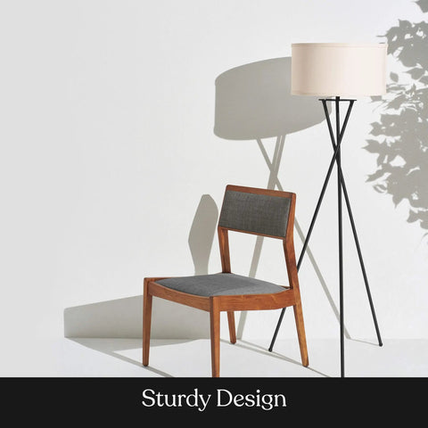 LED Floor Lamp Tall Tripod With Drum Shade In Black Finish And Gold Accents, next to wooden chair, casting shadows