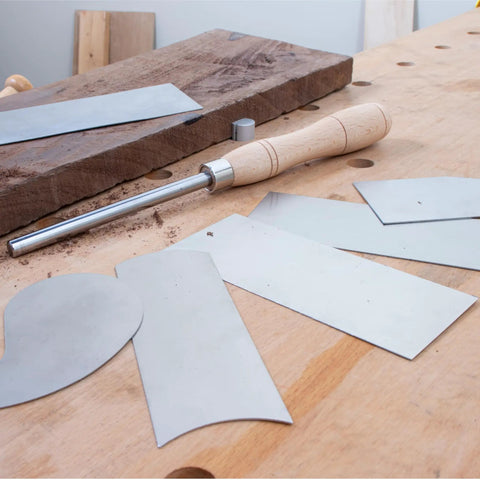 Cabinet Scraper Burnisher With Six Piece Card Scraper Woodworking Set Including Three Rectangle Scrapers One Beveled Curved Concave Gooseneck for smoothing wood surfaces on a workbench.