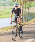 Cyclist riding on a road bike by a river, wearing a helmet and sunglasses, using 2 Pack 700C Bike Inner Tubes 18C 23C 25C With FV48mm Presta Valve