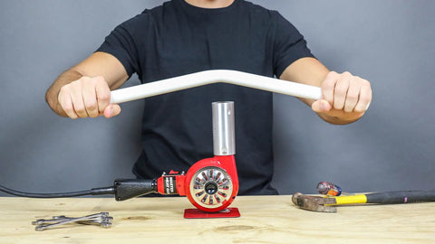 Person using Master-Mite Series Heat Shrink System 220V Red 300 To 500 F Range 1440W Hot Air Tool for bending plastic pipe