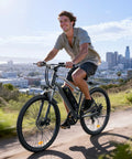 Power Packed 500W Peak Electric Bike For Adults With Up To 60 Mile Range Removable Battery 20 MPH Assist 7 Speed Gearing 26 Inch Tires Shock Absorber Slick Commuter E Bike on a hill path