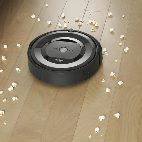 Roomba vacuum on wooden floor with scattered popcorn, compatible with Three Pack High Efficiency Replacement Filters For Roomba E I J Series And Roomba Combo I5 J5 Traps Ninety Nine Percent Pet Dander Allergens And Keeps Your Air Fresh.