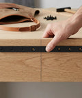 Hand holding Black Metal Joining Plates 4 Pcs Stainless Flat Straight Brackets With Screws on wooden panel for alignment