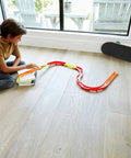 Child playing with Track Builder Unlimited Playset Premium Curve Pack With 16 Component Parts And 1 64 Scale Vehicle on floor