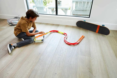 Child playing with Track Builder Unlimited Playset Premium Curve Pack With 16 Component Parts And 1 64 Scale Vehicle on floor