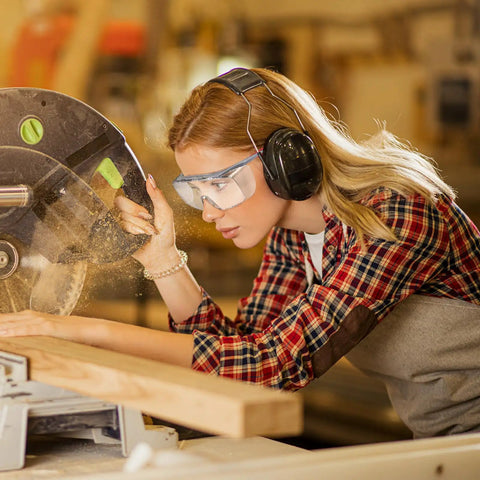Woman in plaid shirt using a saw, wearing Over Glasses Safety Goggles With Anti Fog And Scratch Resistant Lenses ANSI Z87 Certified.