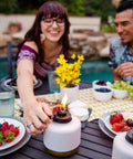Person adjusting flame on Adjustable Flame Glass Votive Table Top Torch for patio, gold dipped gray lantern 6.75 inch.