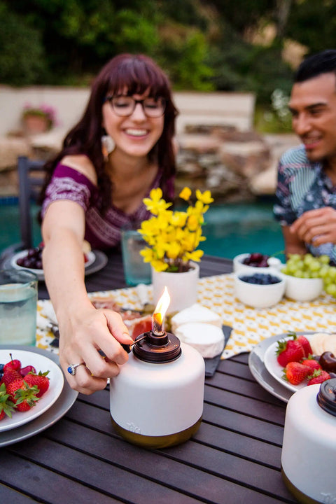 Person adjusting flame on Adjustable Flame Glass Votive Table Top Torch for patio, gold dipped gray lantern 6.75 inch.
