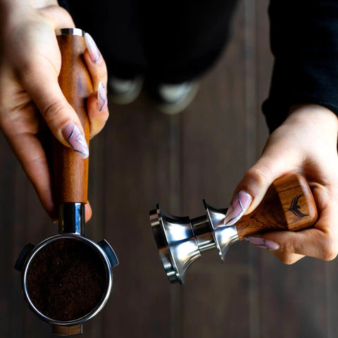 Hella Smooth Breville Espresso Accessories Kit With Bottomless Portafilter Plus Spring Loaded Tamper Featuring Rosewood Knock Box And Wdt Needle Distribution Station, showing hands holding portafilter and tamper.