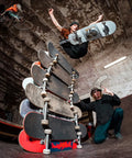 Skateboarder jumps over stacked boards, showcasing 52mm Skateboard Wheels With Bearings And Preinstalled Spacers 90A Black Polyurethane Pack Of 4