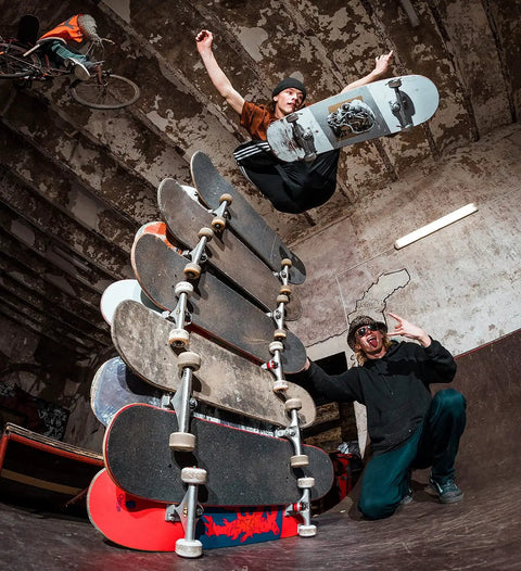 Skateboarder jumps over stacked boards, showcasing 52mm Skateboard Wheels With Bearings And Preinstalled Spacers 90A Black Polyurethane Pack Of 4