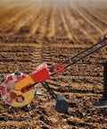 Person using 7 Nozzles Hand Push Roller Seeding Tool With Fertilizer Applicator For Garden Seeding, 9 Inch Planting Spacing